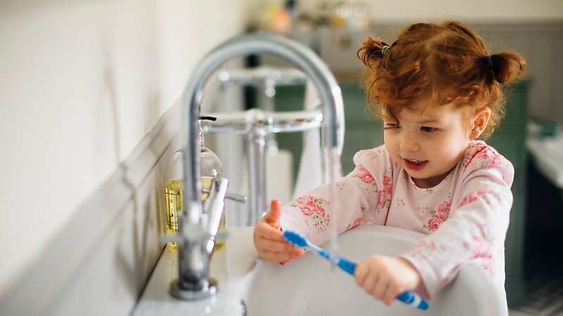 Ett barn borstar tänderna vid handfatet
